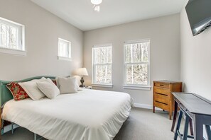 A bedroom with a bed, bedside table, lamp, and a desk with drawers.