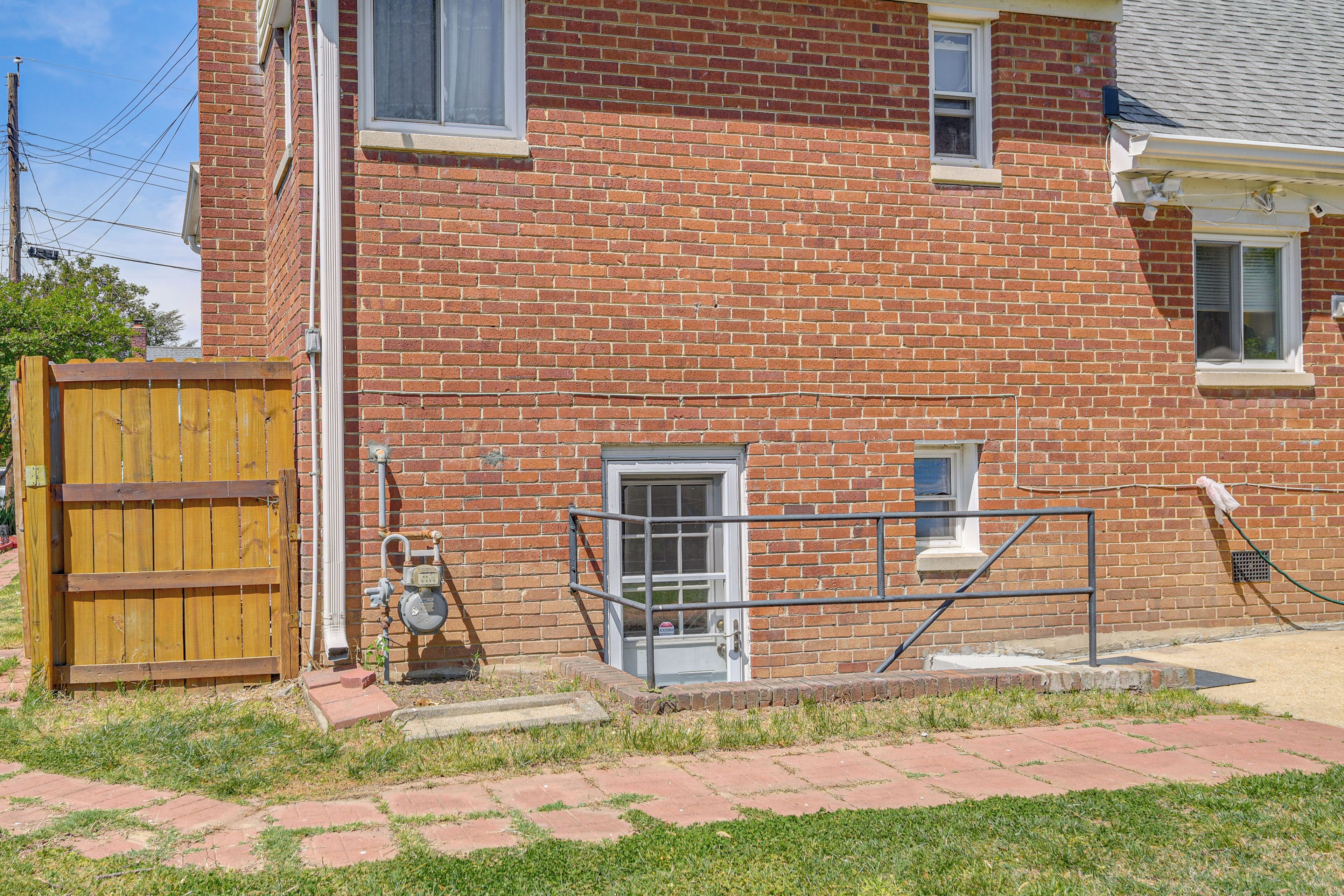 A brick building with a wooden gate, a metal handrail, and a small window.