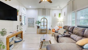 A living room with a ceiling fan, a flat-screen TV, a sofa, a coffee table, and a bookshelf. - Boho Home w/ Deck & Yard in Republic, Pets Welcome (Republic)