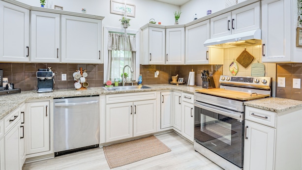 A modern kitchen with white cabinetry, a built-in dishwasher, a stove, and a sink. - Boho Home w/ Deck & Yard in Republic, Pets Welcome (Republic)
