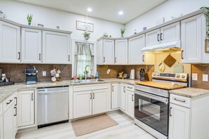 A modern kitchen with white cabinetry, a built-in dishwasher, a stove, and a sink. - Boho Home w/ Deck & Yard in Republic, Pets Welcome (Republic)
