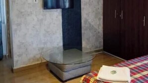 Una camera da letto con un armadio, una televisione a parete e un letto con coperta a quadri.