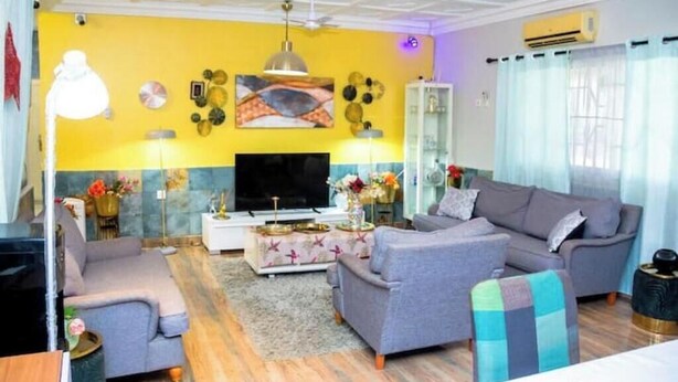 Un soggiorno con divano, televisore, decorazioni a parete e ventilatore a soffitto.