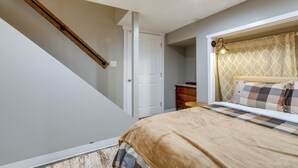 Una camera da letto con un letto, una cassettiera, una porta e una scala.
