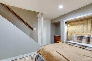 Quarto com cama, penteadeira, porta e escada.