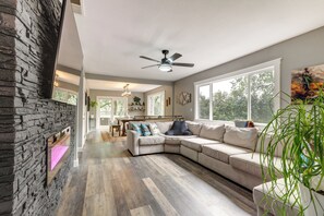 Una sala de estar moderna con un sofá modular, una chimenea y vistas al exterior.