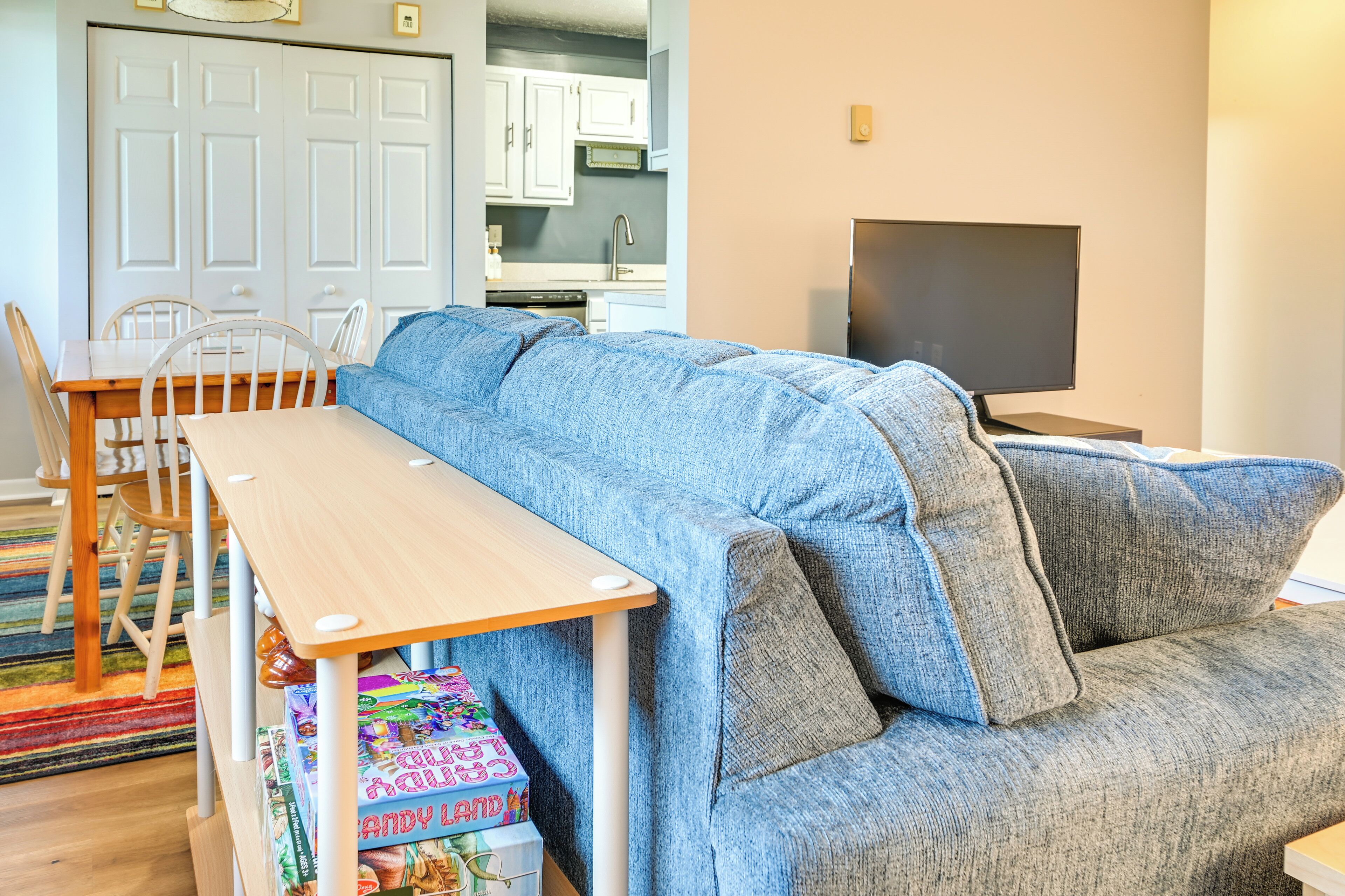 A living room with a blue sofa, a wooden table, and a TV.