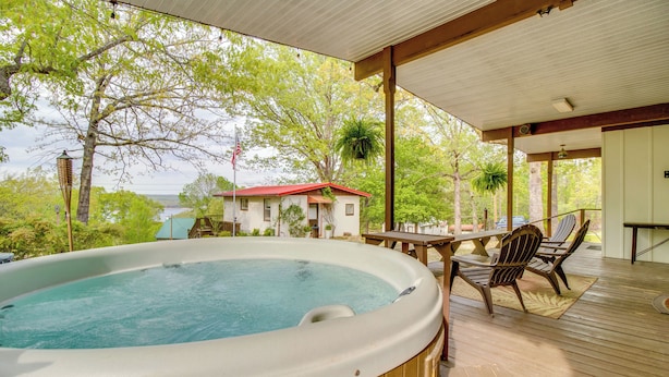 Ein Whirlpool auf einer Holzterrasse mit Blick auf ein Haus und Bäume.