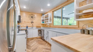 Eine moderne Küche mit Holzwänden, weißen Schränken, einem großen Fenster und einem Fischgrätparkett.