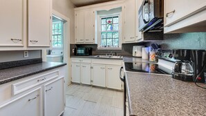 A kitchen with white cabinets, a microwave, a coffee maker, and a stove. - Private Deck & Yard: Pet-friendly Noble Getaway (Noble)