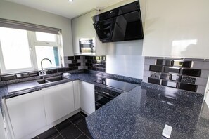 Eine moderne Küche mit einer Granit Arbeitsplatte, Edelstahlgeräten und weißen Schränken.