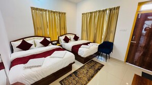 A hotel room with two beds, a blue chair, a patterned rug, and a wooden door. - Hotel Shri Hari And Restaurant (Ukhimath)