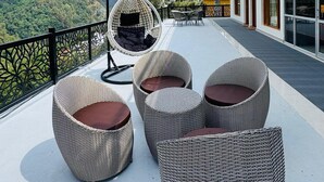 A rooftop terrace with wicker furniture, a hanging chair, and a view of mountains. - Hotel Shri Hari And Restaurant (Ukhimath)
