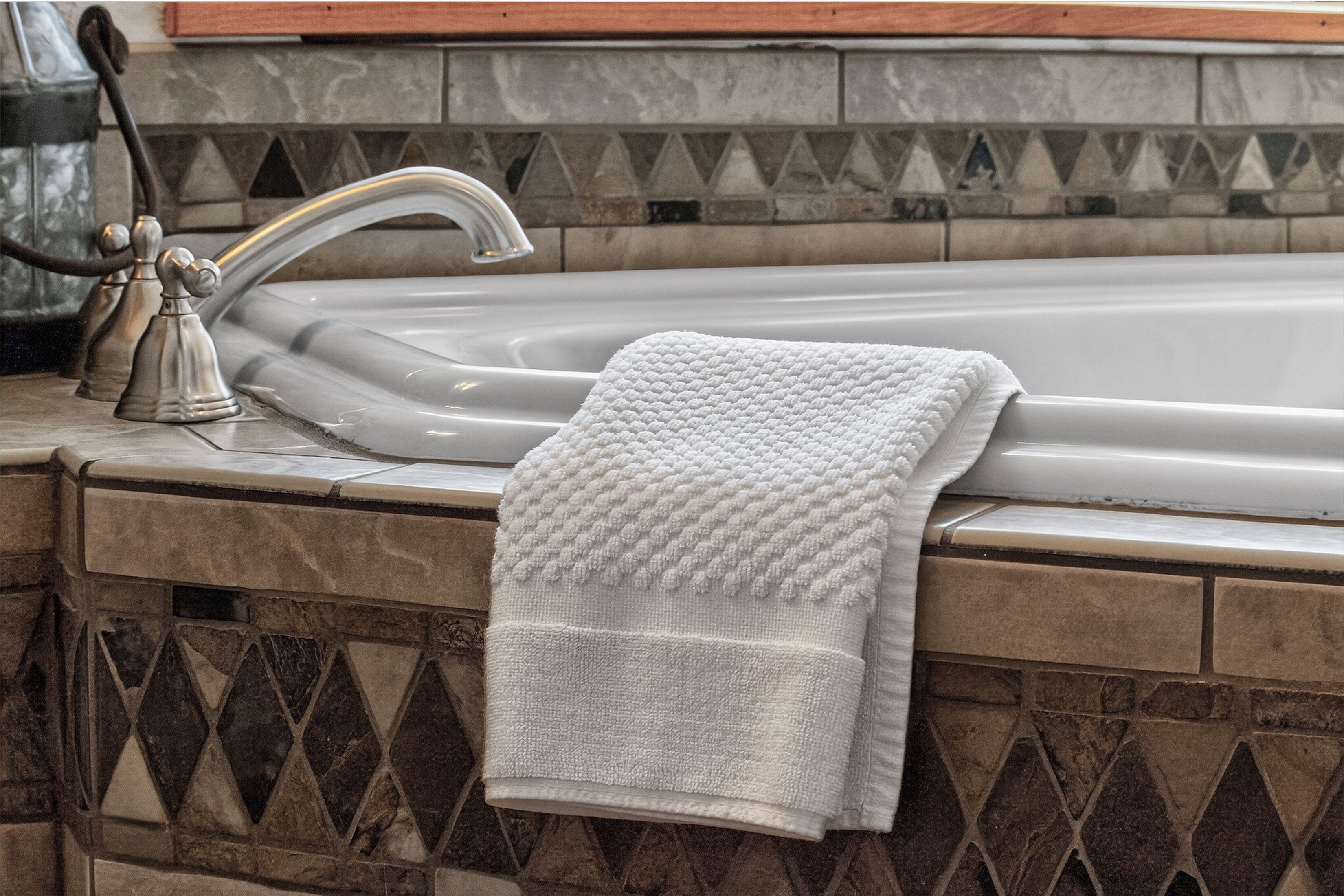 A bathroom with a bathtub, a towel, and a decorative wall.
