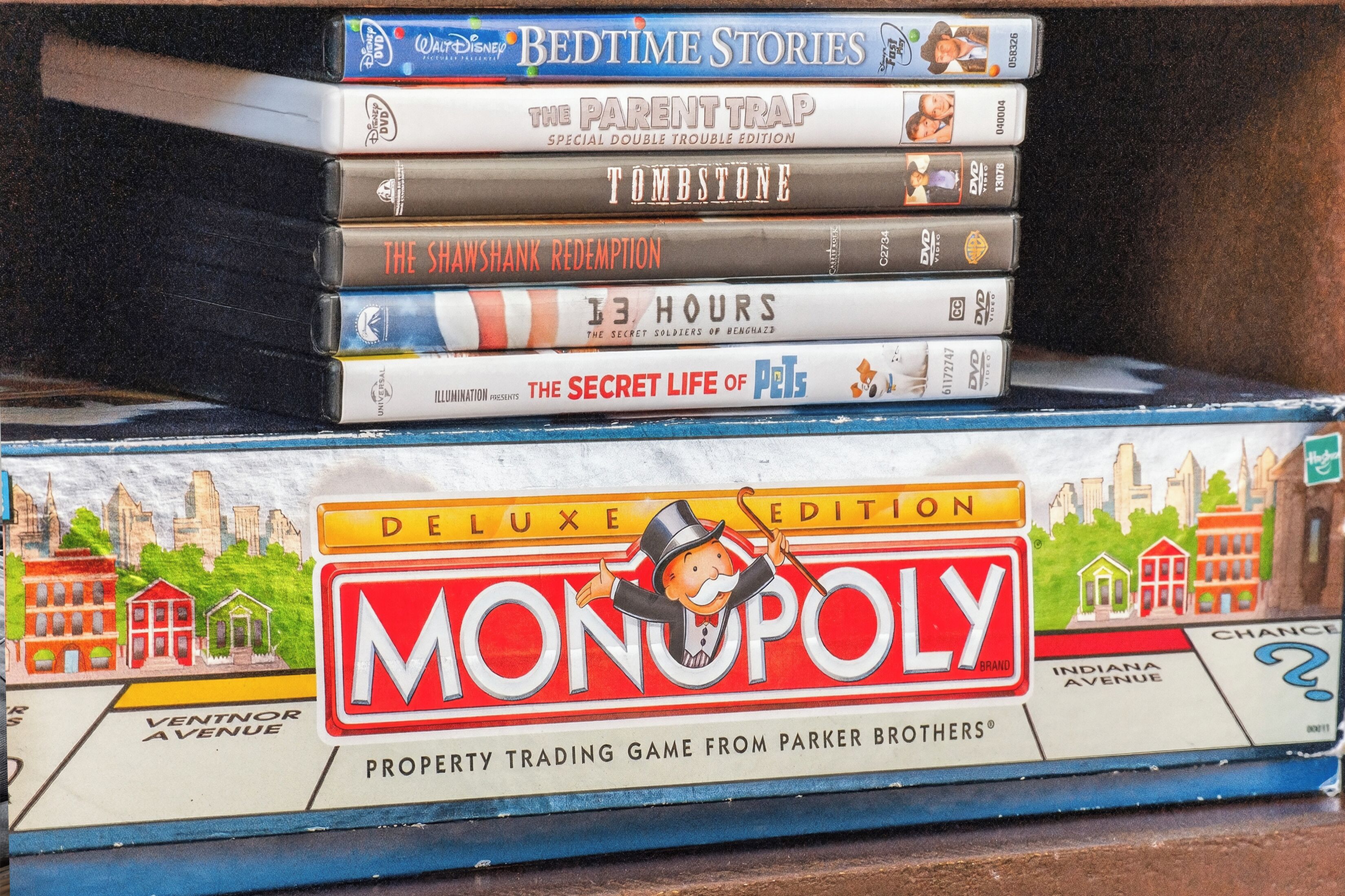A stack of DVDs and a Monopoly game board.