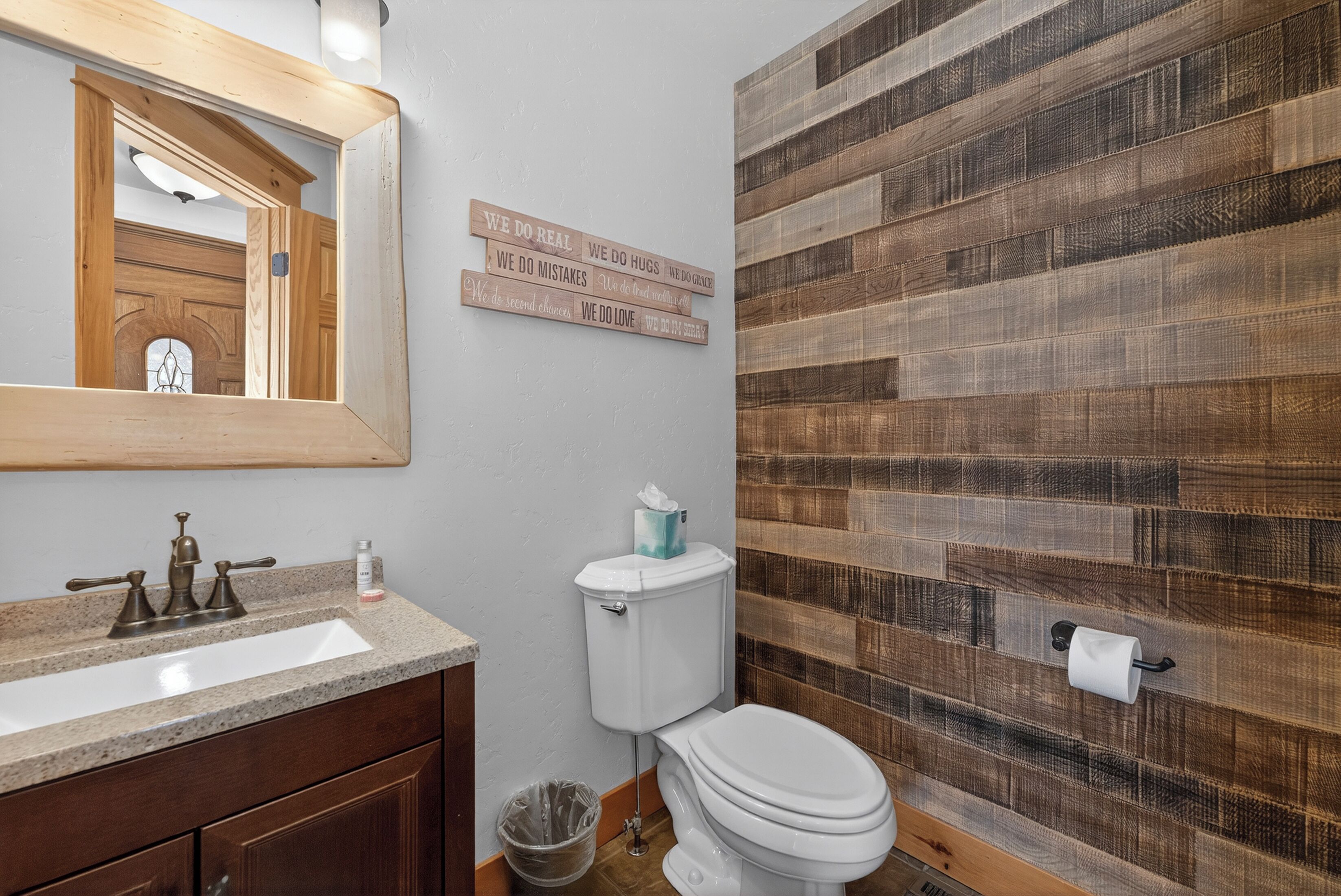 A bathroom with a wooden vanity, a toilet, and a mirror.