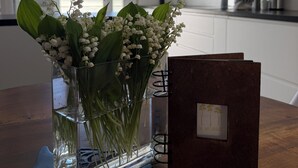 Una cocina con un jarrón de flores blancas sobre la encimera, una mesa de madera y una isla de cocina.