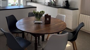 Una cocina moderna con armarios blancos, una mesa redonda de madera y sillas negras y blancas.