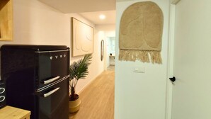 Une cuisine avec un réfrigérateur noir, une plante en pot et un tableau encadré accroché au mur.