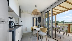 Cozinha moderna com fogão embutido, espaço de jantar com mesa e cadeiras, e uma grande porta de vidro deslizante que dá para um pátio externo.