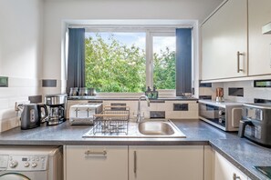 Eine moderne Küche mit Fenster, Edelstahlgeräten und Geschirrspüler.