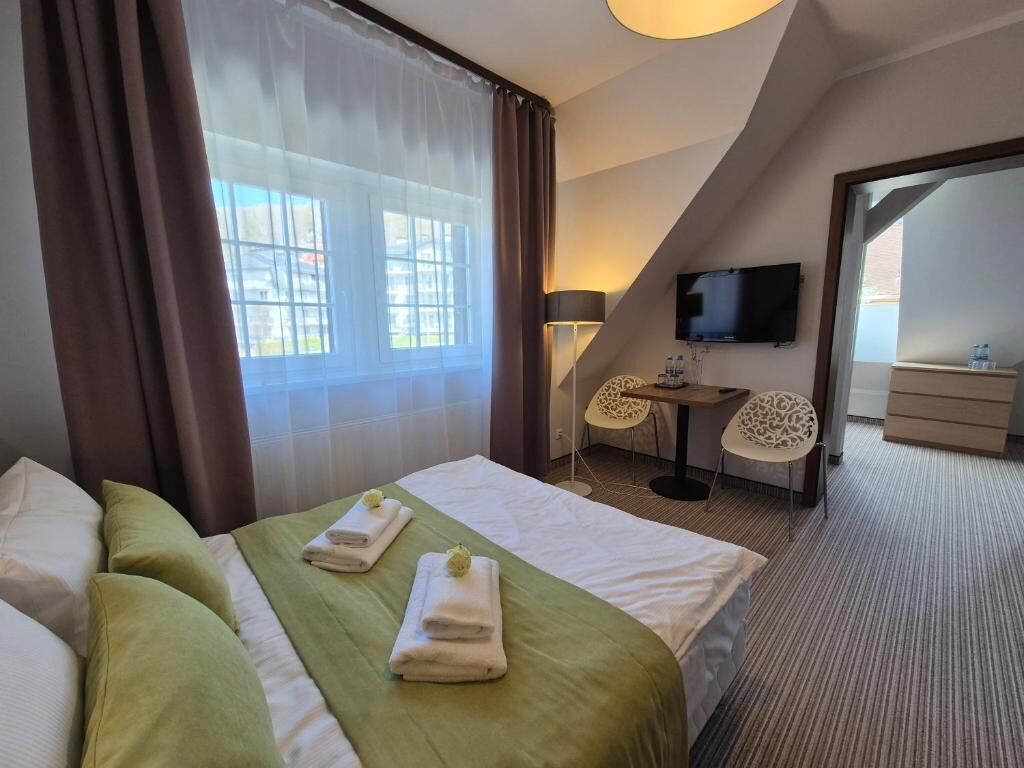 Hotellihuone, jossa on sänky, televisio, työpöytä ja tuoli.