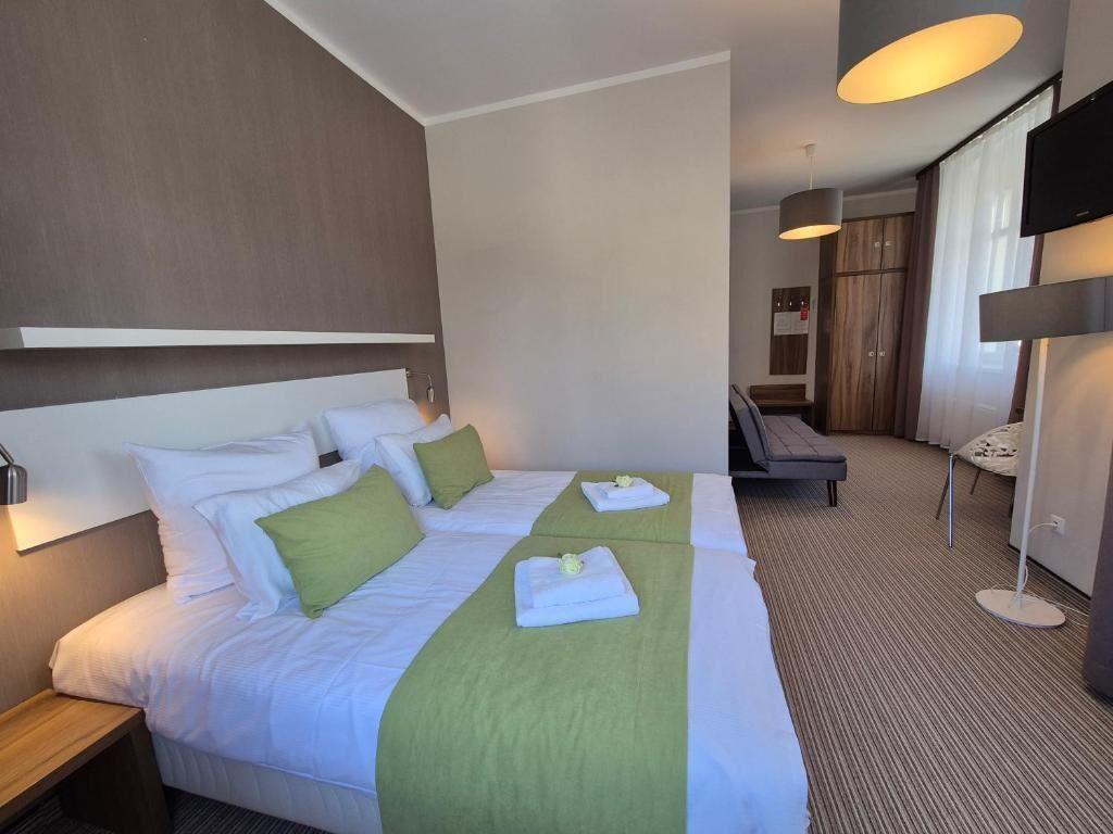 A hotel room with a large bed, bedside tables, a TV, and a seating area.