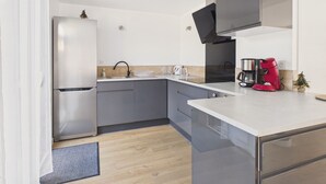 Una cocina moderna con refrigerador, lavamanos y cafetera.