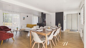 Una sala de estar moderna con comedor, suelo de madera y un amplio ventanal corredera.