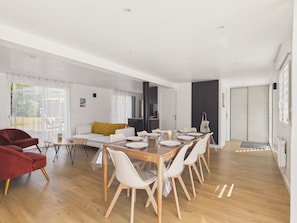 Un salon moderne avec un coin repas, un plancher en bois et une grande porte coulissante.