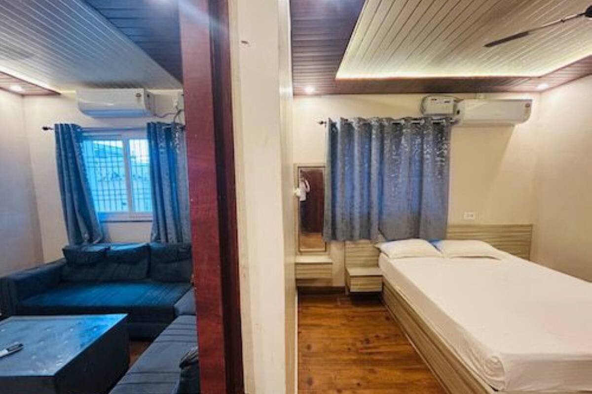 A compact room with a sofa, a bed, a small table, and a wooden floor.