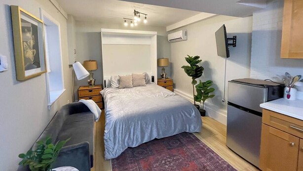 Une chambre compacte comprenant un lit, des tables de chevet, un bureau, une chaise, une petite kitchenette et un téléviseur.