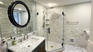 Une salle de bain moderne avec une douche à parois de verre, un grand miroir et un lavabo en marbre.