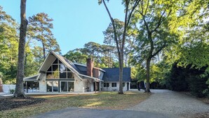 Una casa moderna con un amplio ventanal, rodeada de árboles.