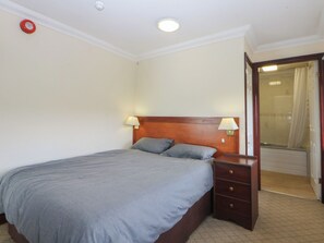 A hotel room with a bed, bedside tables, and a bathroom visible through an open door. - Seaview Apartment 5 (Y Felinheli)
