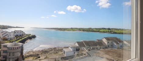 A coastal view with buildings, a beach, and a clear sky.