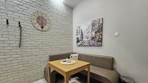 A living room with a brick wall, a wooden table, a sofa, a clock, and a painting. - Stylish&Beutiful
Vitosha Blvd (Sofia)