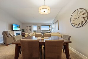 A dining area with a wooden table and chairs, a television, and a large wall clock. - 935 - Beach Days are the Best Days (Westport)
