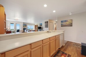A modern kitchen with a long countertop, built-in cabinets, a dishwasher, and a view of the outdoors. - 422 - Ocean View Retreat with Incredible View (Westport)