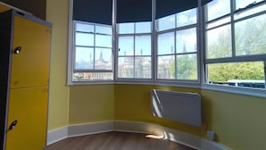 A corner room with a bay window, a radiator, and a yellow wardrobe. - Safestay Brighton Royal Pavilion (Brighton)