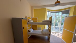 A bunk bed room with a wardrobe, a window with a view, and a hanging light fixture. - Safestay Brighton Royal Pavilion (Brighton)