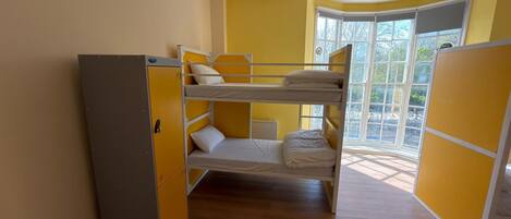 A bunk bed room with a wardrobe, a window with a view, and a hanging light fixture.