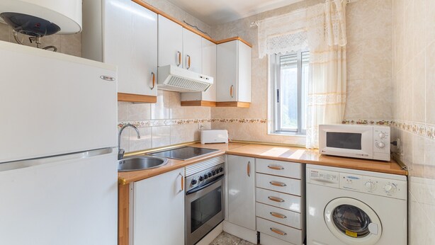 Una cocina compacta equipada con refrigerador, estufa, microondas y lavadora.