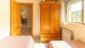 Un dormitorio con dos camas, un armario de madera, un radiador y una ventana con vistas.