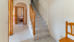 Una escalera con barandillas de madera, un candelabro y una silla.