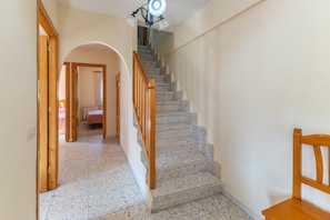 Una escalera con barandillas de madera, un candelabro y una silla.