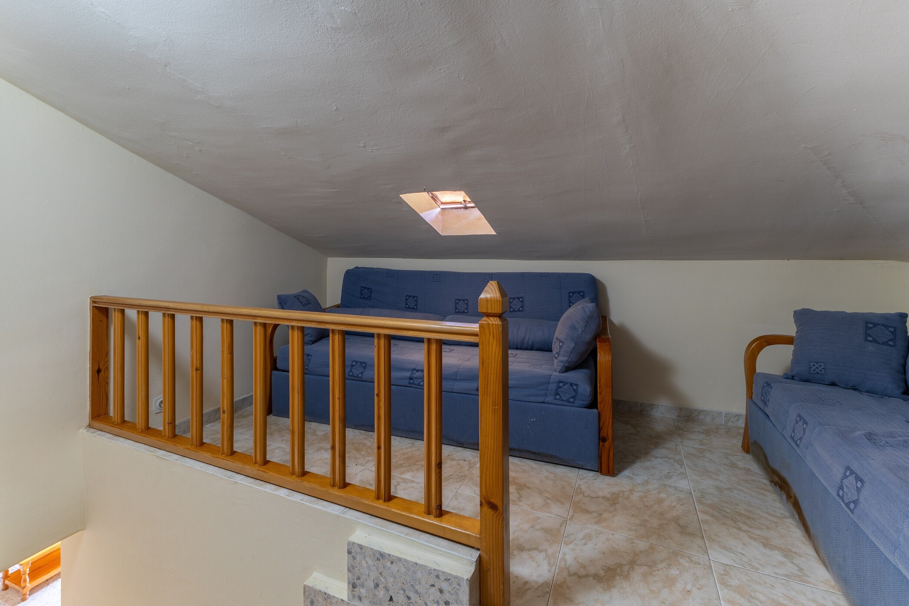 Ein Schlafzimmer mit einer Holztreppe, einem blauen Sofa und einem Bett mit einem gemusterten Überwurf.