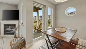 Habitación con televisión, chimenea, mesa de comedor, silla de mimbre y vista a un edificio a través de una ventana.