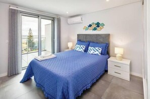 Ein Schlafzimmer mit einem großen Bett, einem Nachttisch, einem Fenster mit Vorhängen und einer Wanddekoration.