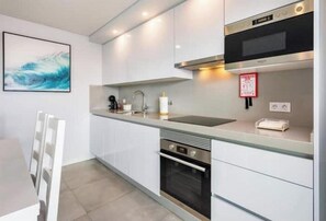 Eine moderne Küche mit weißen Schränken, einem Edelstahlbackofen, einer Mikrowelle und einem Spülbecken.